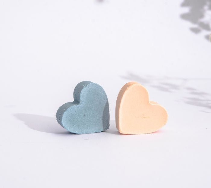 Two little cute hart shaped soaps. One is pastel orange ant the other one is blue. They made of pure sweet orange, lemon and citronella essential oil and Croatian extra virgin olive oil. The natural handmade soaps are on the white background.