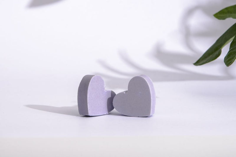 Two little cute hart shaped purple soaps made of pure lavender essential oil and Croatian extra virgin olive oil on white background with green leaf.