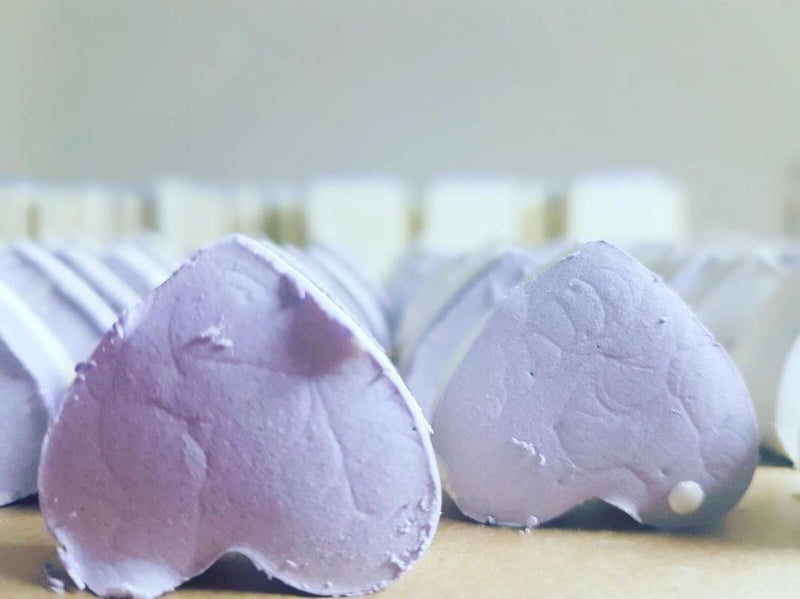 Close up of natural handmade, cold processed, lavender and olive oil soap on wooden table in soapery. Heart shaped purple soaps. 